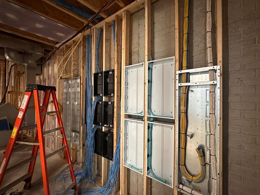 Construction room containing structured wiring panels and a bright orange stepladder