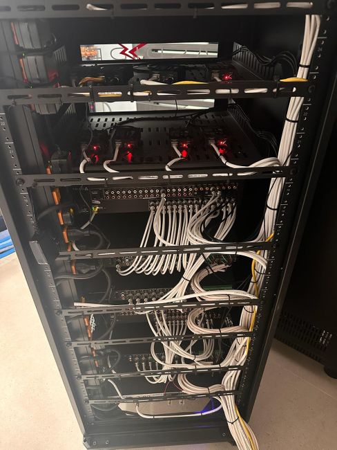 Back side of open audio visual component rack with complex neatly tied patch cables