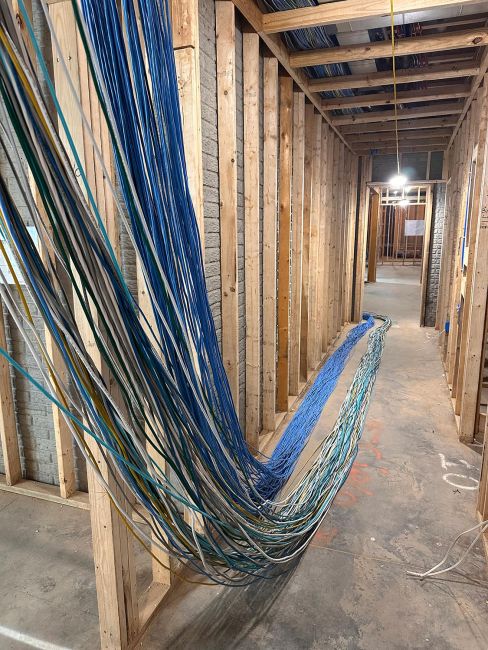 Thick drapes of blue and white network cabling strung along exposed wooden wall studs
