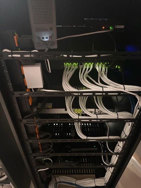 Internet network switch inside server rack with numerous plugged-in white patch cables