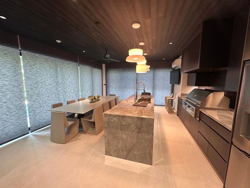 Minimalist open kitchen and dining area with large roller shades lowered over windows