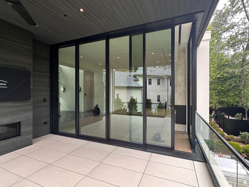 Large sliding glass doors on a contemporary terrace overlooking trees and houses