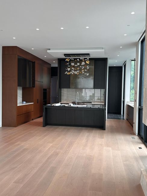 Minimalist modern kitchen with dark cabinets, center island, and wood flooring