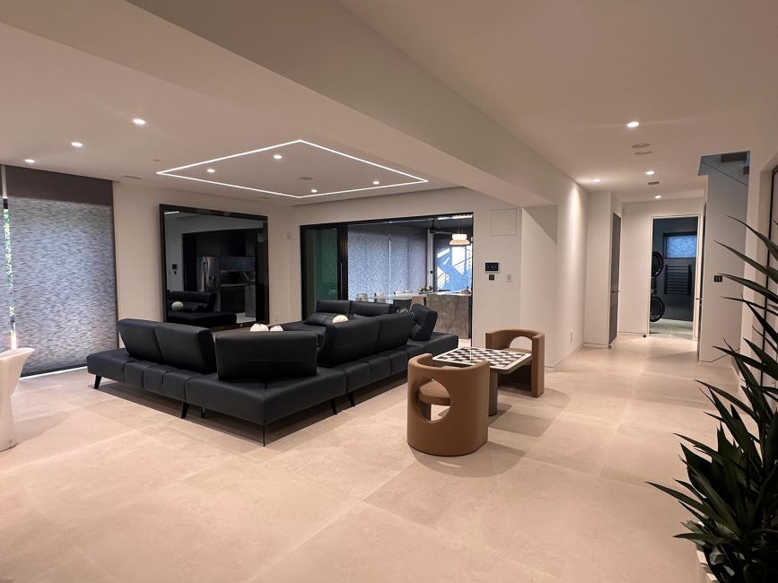 Open basement living room with black sectional sofa, recessed lighting, and game table