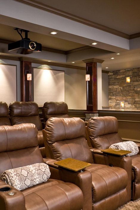 Brown leather home theater recliners with attached trays and a ceiling-mounted projector