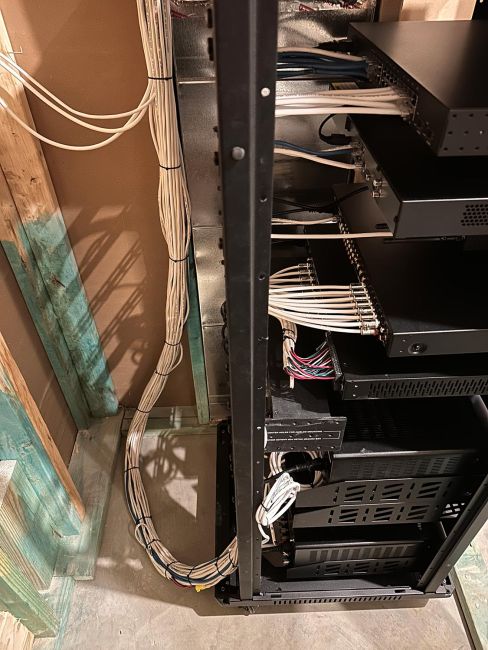 Clean and organized indoor AV equipment server rack featuring neatly bundled white Ethernet cables and audio-visual components.
