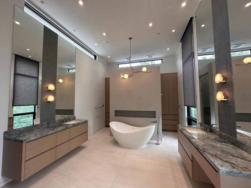 Luxury bathroom with freestanding tub, stone vanities, large mirrors, and modern lighting