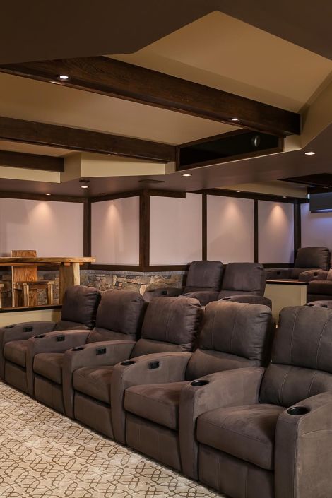 Multi-row home cinema with dark brown suede reclining seats and rustic wood ceiling beams