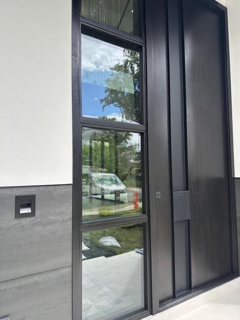 Front entry door with tall glass window panes and dark metallic panels