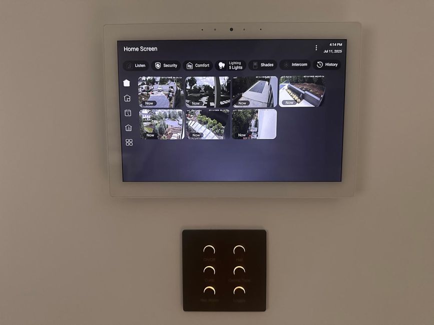 Smart home automation touchscreen panel on wall above a black lighting keypad controller