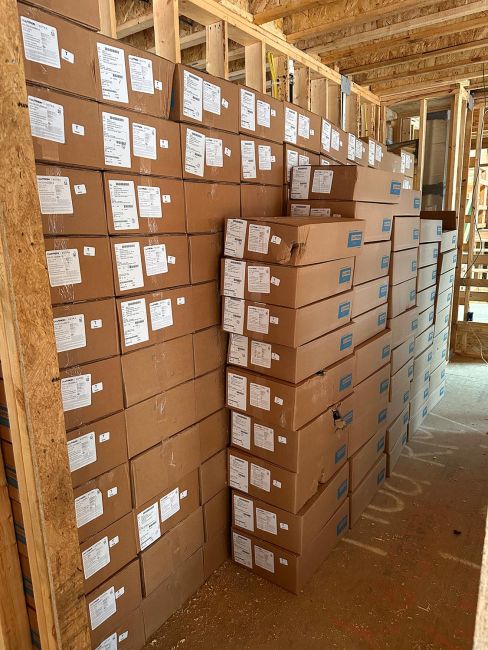 Tall stacks of generic cardboard product boxes arranged neatly inside a framed building room