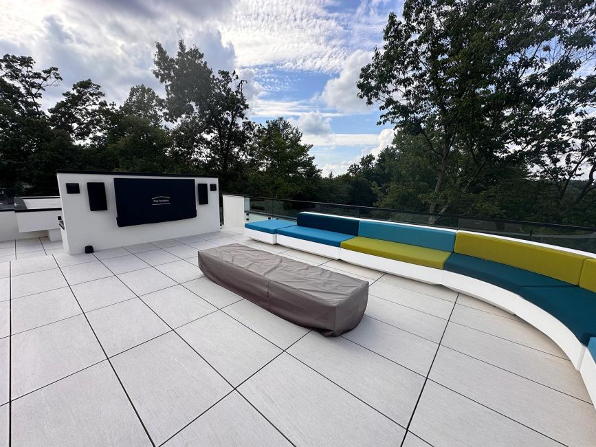 Rooftop patio with large modular colorful sectional sofa and gray tiled flooring