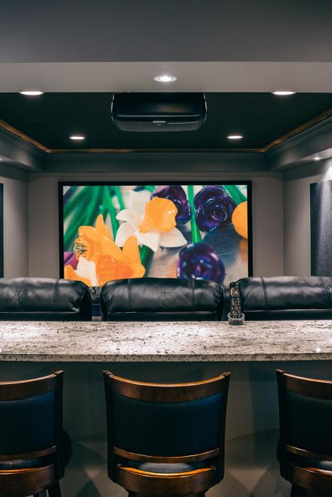 Home theater view from behind a marble bar counter looking toward a screen with floral images