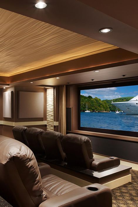 Cozy home theater with plush brown leather seating, tray ceiling lighting, and a big screen
