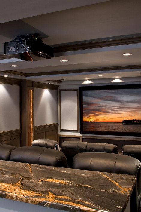 Luxury home cinema with a black projector, dark marble bar top, and a sunset on screen