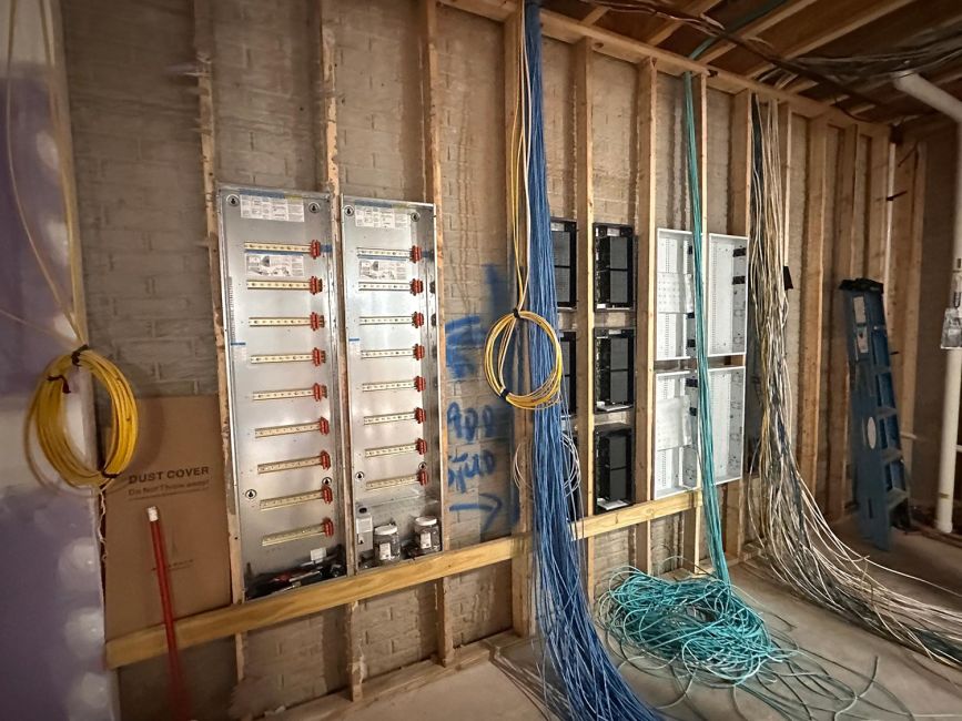 Electrical service wall under construction featuring metal components and loose wire bundles