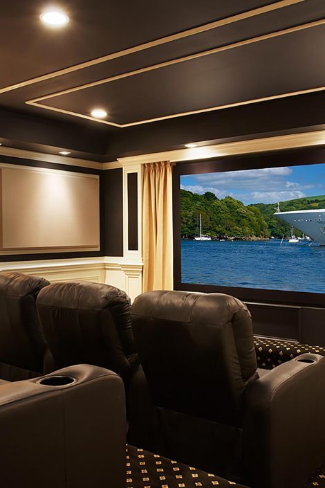 Widescreen display showing a cruise ship on water behind black leather theater seats