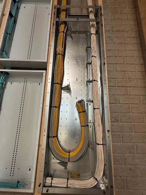 Open vertical metal cable tray containing organized runs of white and yellow cables